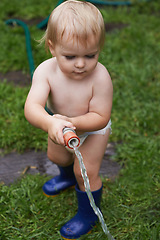 Image showing Child, gardening and water grass with hose and learning to care for backyard and lawn. Kid, outdoor and play with hosepipe in summer, nature or environment and helping with sustainable growth at home
