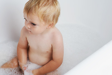 Image showing Baby in bath, clean with bubbles and soap for morning routine with health, wellness and body care in home. Cute toddler washing in foam with hygiene, relax and calm child sitting in water in bathroom