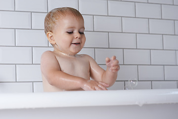 Image showing Baby, child and playing with bubbles in bath of water for morning routine, skincare and wellness at home. Happy boy, kid and cleaning in tub with soap, foam and washing for fun, hygiene and bathroom