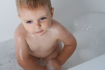 Image showing Baby, child and bubbles in bath of water for morning routine, skincare and cleaning at home from above. Boy, wet kid and toddler thinking in bathtub of soap, foam and washing for hygiene in bathroom