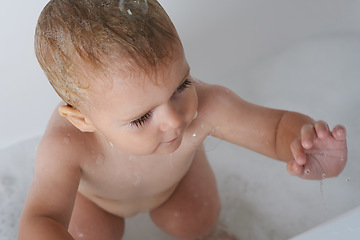 Image showing Baby, child and play with bubbles in bath of water for morning routine, skincare and wellness at home from above. Boy, kid and cleaning in tub with soap, foam and bathroom for fun, hygiene or washing