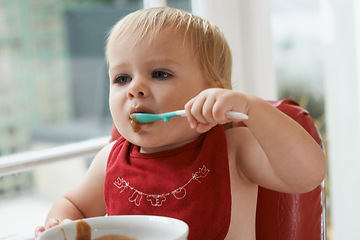 Image showing Hungry, sweet and baby eating porridge for health, nutrition or child development at home. Food, cute and girl toddler or kid enjoying an organic puree meal for lunch or dinner in high chair at house