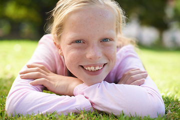 Image showing Happy, portrait and girl child lying in grass for fun, play and adventure in nature. Face, smile and kid in garden with positive attitude, mindset and excited for exploring, learning or weekend break