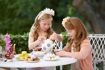 Image showing Girl, friends and tea party in backyard or cupcakes for dessert or dress up game, fantasy or playing. Female people, siblings and pot for hot drink in garden for summer event fun, lunch or birthday