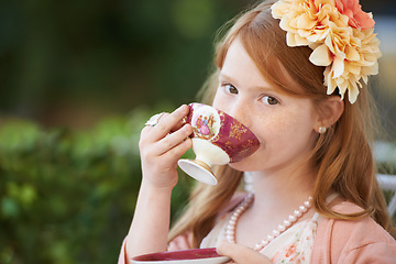 Image showing Girl, child and portrait of drinking tea in garden with party for birthday, celebration and playing outdoor. Person, kid and porcelain cup in backyard with dress up, beverage and role play with fun