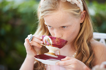 Image showing Girl, kid and drinking tea in garden with party for birthday, celebration and playing outdoor in home. Person, child and porcelain cup in backyard of house with dress up, beverage and role play fun