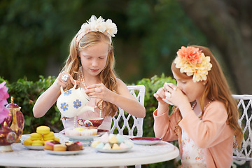 Image showing Girls, children and tea party or outdoor fun for fantasy play in garden for cake snack, birthday or game. Kids, sisters and fancy dress up in nature or summer bonding in backyard, beverage or dessert