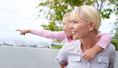 Image showing Happy, piggyback and mother with child pointing for sightseeing in nature, park or garden. Smile, fun and young mom carrying girl kid for bonding and playing together on an adventure in a field.