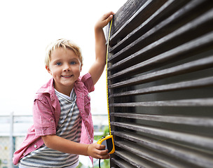 Image showing Smile, measuring tape and portrait child doing maintenance on wood gate for fun or learning. Happy, equipment and young boy kid working on repairs with tool for home improvement outdoor at house.