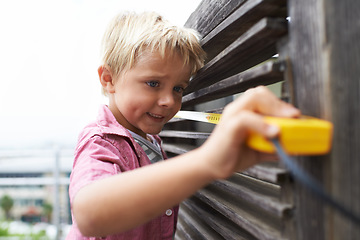 Image showing Happy, measuring tape and young child doing maintenance on wood gate for fun or learning. Smile, equipment and cute boy kid working on repairs with tool for home improvement outdoor at house.