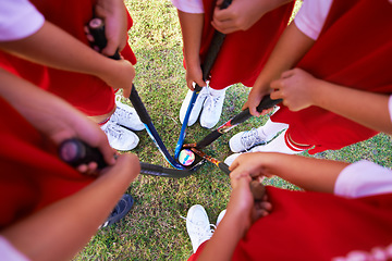 Image showing Children, hockey team and circle above with ball on green grass for sports, match or game together. Top view closeup of kids, player hands and huddle on field for teamwork or outdoor unity in nature