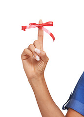 Image showing Finger, ribbon and red bow on for reminder of event, commitment or sign remember task in studio. Attention, symbol and icon on hand to notice date of appointment or helping to alert memory of person