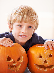 Image showing Boy, portrait and happy with pumpkin for halloween, celebration or decoration in kitchen of apartment or home. Kid, face and smile with vegetable for preparation, holiday or creative event in house