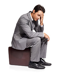 Image showing Thinking, stress and business man with briefcase in studio for travel, fail or mistake on white background. Doubt, anxiety and person sitting on a bag with headache, disaster or compliance problem