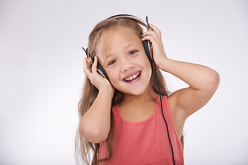Image showing Child, music and portrait of girl with headphones in studio for audio, subscription and streaming multimedia on white background. Excited kid listening to podcast, hearing sound and radio connection