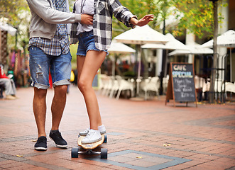 Image showing Skateboard, legs and couple of friends teaching partner how to ride, exercise lesson or training in urban city. Fun activity, cardio fitness and feet of people helping, support and coaching to skate