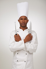 Image showing Portrait, african chef and knives in studio in hospitality career and confident cook in food industry. Black man, face and serious in skill in kitchen utensils and uniform by hat by white background