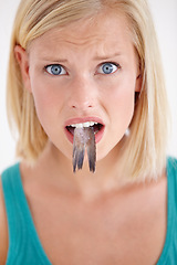 Image showing Confused, woman and portrait eating fish, tail and surprise on white background of studio. Crazy, diet and person with doubt in weird seafood, cuisine and taste gross or strange food in mouth