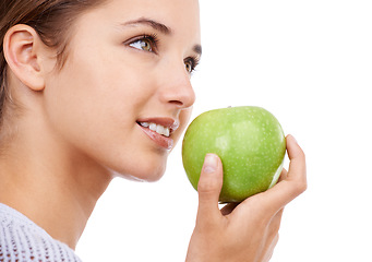 Image showing Woman, eating and apple in hand, nutrition and health with snack, diet for weight loss and detox on white background. Healthy food, wellness and green fruit, vegan and organic with smile in studio