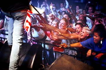 Image showing Music festival, stage and fans of musician at performance, event and excited screaming for rockstar. Concert, crowd and people in audience stretching and listening to artist in band with freedom