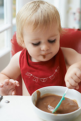 Image showing High chair meal, spoon and baby eating in a house with diet, nutrition and child, wellness or development. Food, messy eater and boy kid curious about breakfast porridge, playing or learning at home
