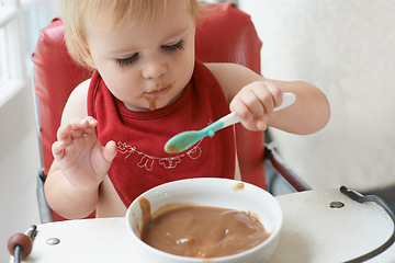Image showing High chair meal, baby and eating spoon in a house with diet, nutrition and child, wellness or development. Food, messy eater and boy kid curious about breakfast cereal, playing or learning at home