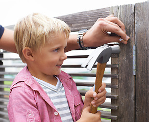 Image showing Smile, hammer and young child doing maintenance on wood gate for fun or learning. Happy, equipment and cute boy kid working on repairs with tool for home improvement outdoor at modern house.