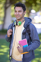 Image showing Young man, headphones and book on campus and scholarship opportunity in commitment at college. Student, smile and audio electronics by backpack, relax and university outdoor for learning in nature