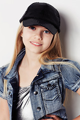 Image showing Child, portrait and fashion in studio, confident and cool by white background. Female person, girl and casual clothing or style by backdrop, kid and denim jacket pride or smiling for trendy cap