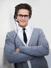 Image showing Business man, call center and headphones in portrait, smile and microphone by wall background. Telemarketing employee, worker or person with mic, pride and contact us with voip for technical support