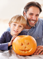 Image showing Father, portrait and kid with pumpkin to celebrate halloween, fun craft and creativity at home. Happy boy child, dad and family carving face in orange vegetable, holiday lantern and party decoration