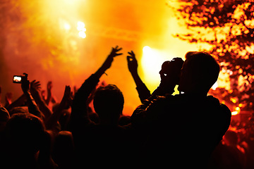 Image showing People, silhouette and camera with crowd at festival, music or concert for pictures, social media or news article. Dark, photographer or person with bright, orange and lighting for rock performance