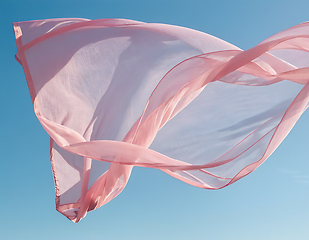 Image showing Flying pink fabric wave on blue sky background and illuminated b