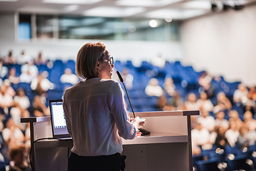 Image showing Female speaker giving a talk on corporate business conference. Unrecognizable people in audience at conference hall. Business and Entrepreneurship event.