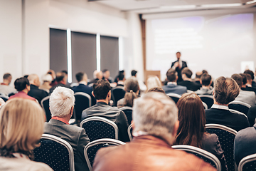 Image showing Speaker giving a talk in conference hall at business event. Rear view of unrecognizable people in audience at the conference hall. Business and entrepreneurship concept.