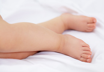 Image showing Feet, baby and legs of kid on bed for sleep, calm break and relax in nursery room at home. Closeup, foot and toes of tired young child asleep for newborn development, healthy childhood growth or rest