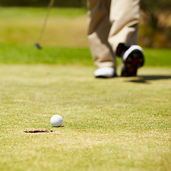 Image showing Golf, ball and hole on a green in summer for sports, recreation or leisure closeup for hobby. Grass, ground or field with a golfer walking on a course during a game of competition or training
