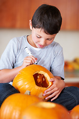 Image showing Halloween, pumpkin and boy kid in the kitchen for holiday celebration at modern home. Creative, smile and happy young child and carving vegetable for fun, decoration or tradition at family house.