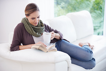 Image showing Woman, book and reading with coffee on sofa to relax for story, novel and knowledge in living room at home. Lady, fiction books and break with cup of tea for literature, hobby or comfortable on couch