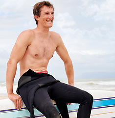 Image showing Vision, smile and shirtless man with surfboard on beach in wetsuit for sports, travel or fitness. Nature, thinking and body of young surfer on sand by ocean or sea for exercise, training and workout