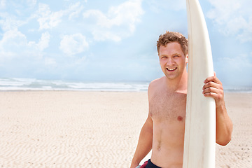 Image showing Portrait, smile on beach and man with surfboard on blue sky for sports, travel or fitness. Nature, space and shirtless young surfer on sand by ocean or sea for exercise, training and workout
