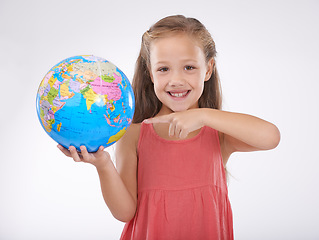 Image showing Child, pointing to globe in studio with world, planets and city for education, geography and portrait. Student, girl kid and travel map with smile for earth day support or ecology on white background