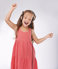 Image showing Girl kid, dance and singing with headphones in studio for streaming audio, multimedia and celebration on white background. Excited young child with energy listening to music, hearing sound and radio