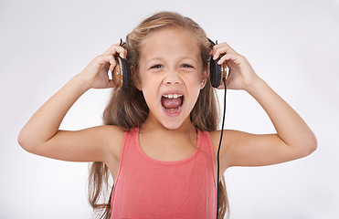 Image showing Girl, headphones and screaming for noise in portrait, autism and sensory overstimulation in studio. Female person, kid and yelling for sound on white background, stress and frustration in childhood