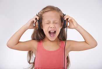 Image showing Child, headphones and screaming in studio for music entertainment, rock or streaming. Female person, girl and shout for listening audio or radio noise or loud sing, white background or mockup space