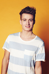 Image showing Portrait, fashion and man with style, smile and confident guy on an orange studio background. Face, person and model with student, casual outfit and stylish clothes with gen z, t shirt and aesthetic