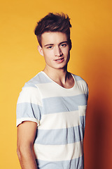 Image showing Portrait, fashion and man with style, trendy and confident guy on an orange studio background. Face, person and model with casual outfit, sexy and stylish clothes with gen z, t shirt and aesthetic