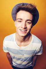 Image showing Portrait, smile and man with fashion, stylish clothes and cool guy on an orange studio background. Face, happy person or model with accessory, student and aesthetic with casual outfit, trendy and hat