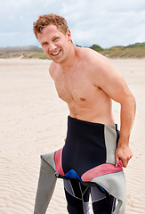 Image showing Portrait, smile and surfer man in wetsuit at beach for sports, fitness or exercise on summer vacation. Travel, health and sand with happy young person getting for training, workout or surfing