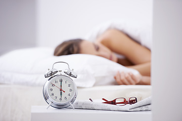 Image showing Sleeping, morning and woman in bed with alarm for snooze, wake up and start day in home. Lazy, tired and person resting, dreaming and relaxing in bedroom with time, clock and glasses in house